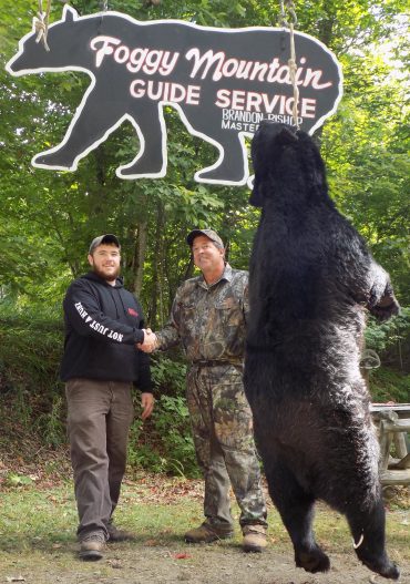 Brandon Bishop owner of Foggy Mountain congratulating a successful bear hunter